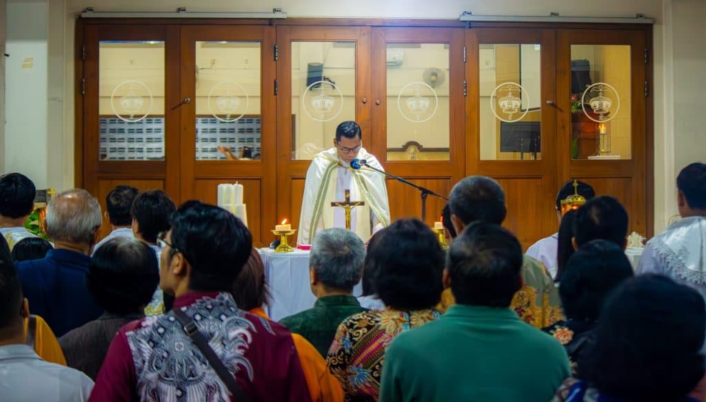 Pastor memimpin ibadah di depan jemaat yang khusyuk berdoa